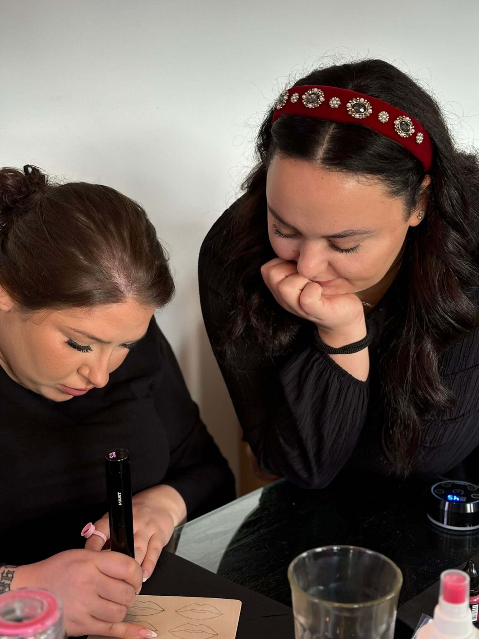 Two women engaged in creative activities, one drawing while the other watches intently.