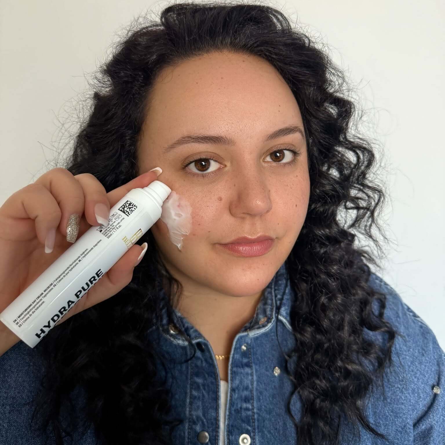 Woman using Hydra Pure moisturizing cream on her face, showcasing skincare routine for healthy skin.